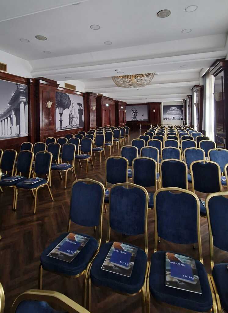 Sala meeting allestita con sedioline blu e oro in sala plenaria al Radisson Blu GHR Roma